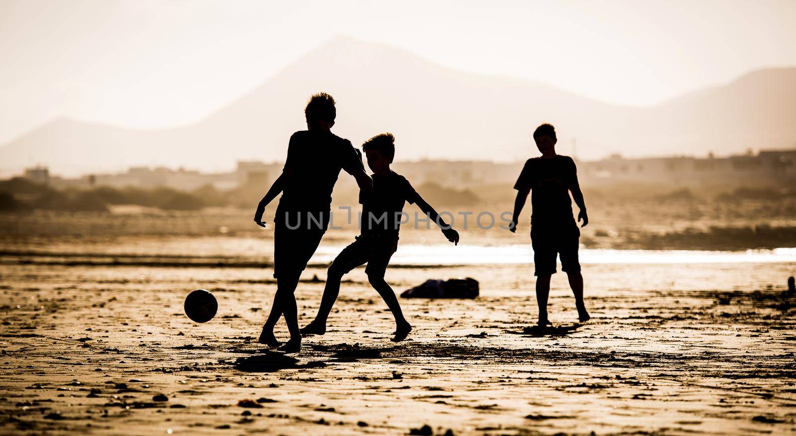 Silhouette of children on the beach with a ball