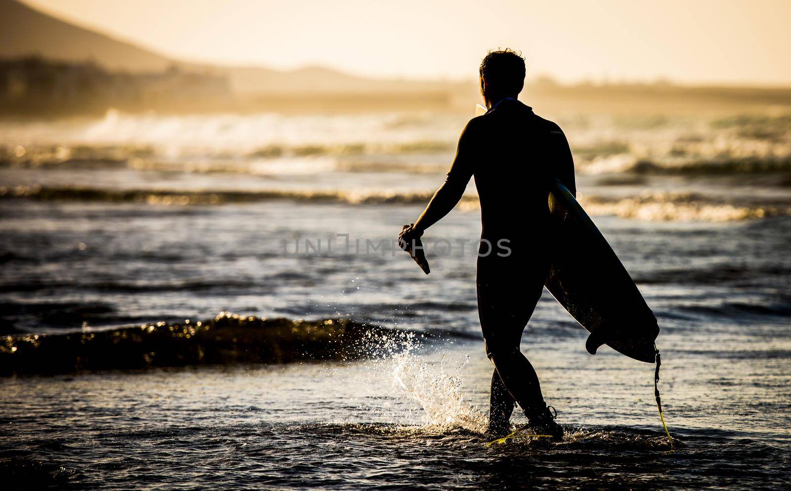 Silhouette of man with a surfboard on the beach