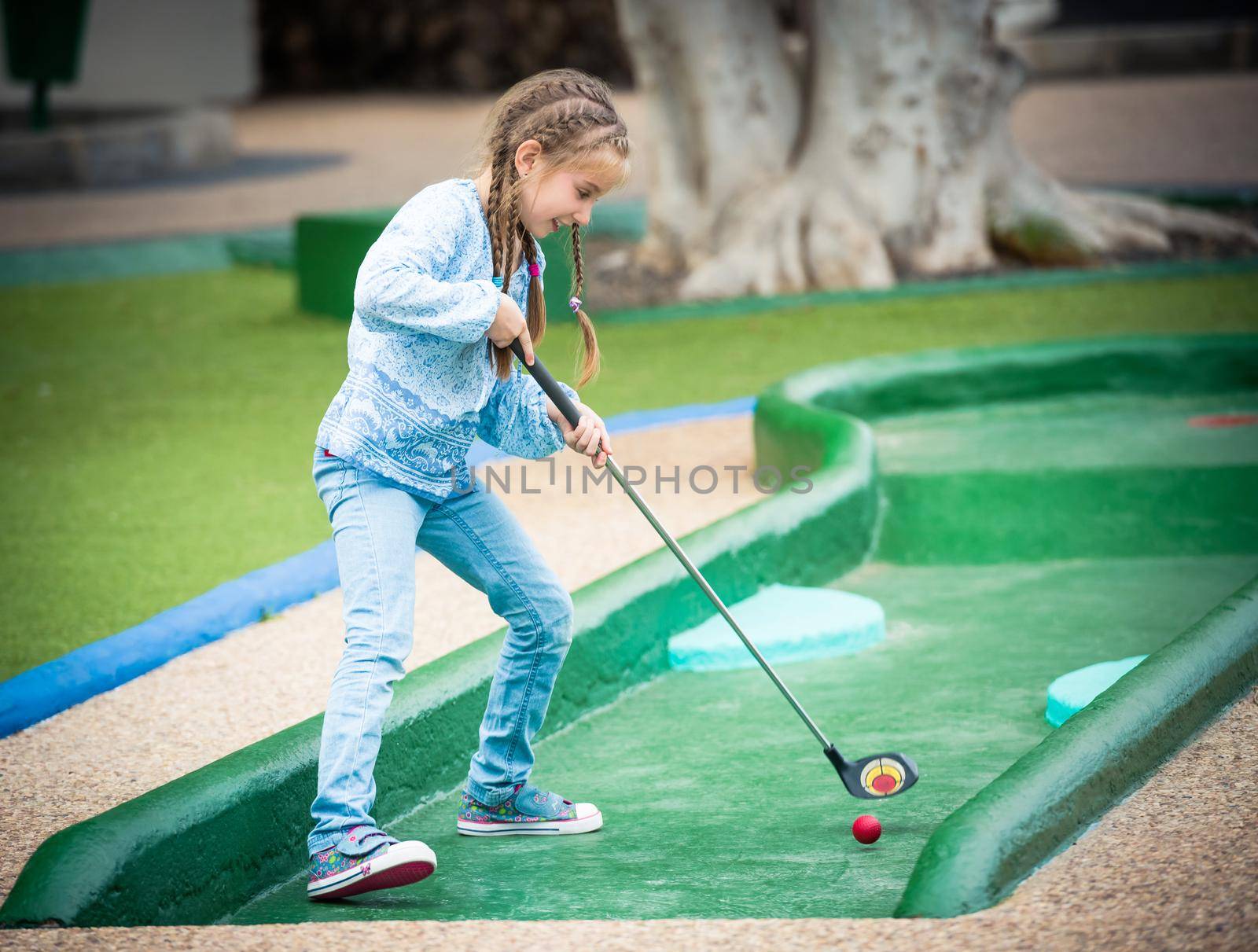 little girl playing golf outdoors