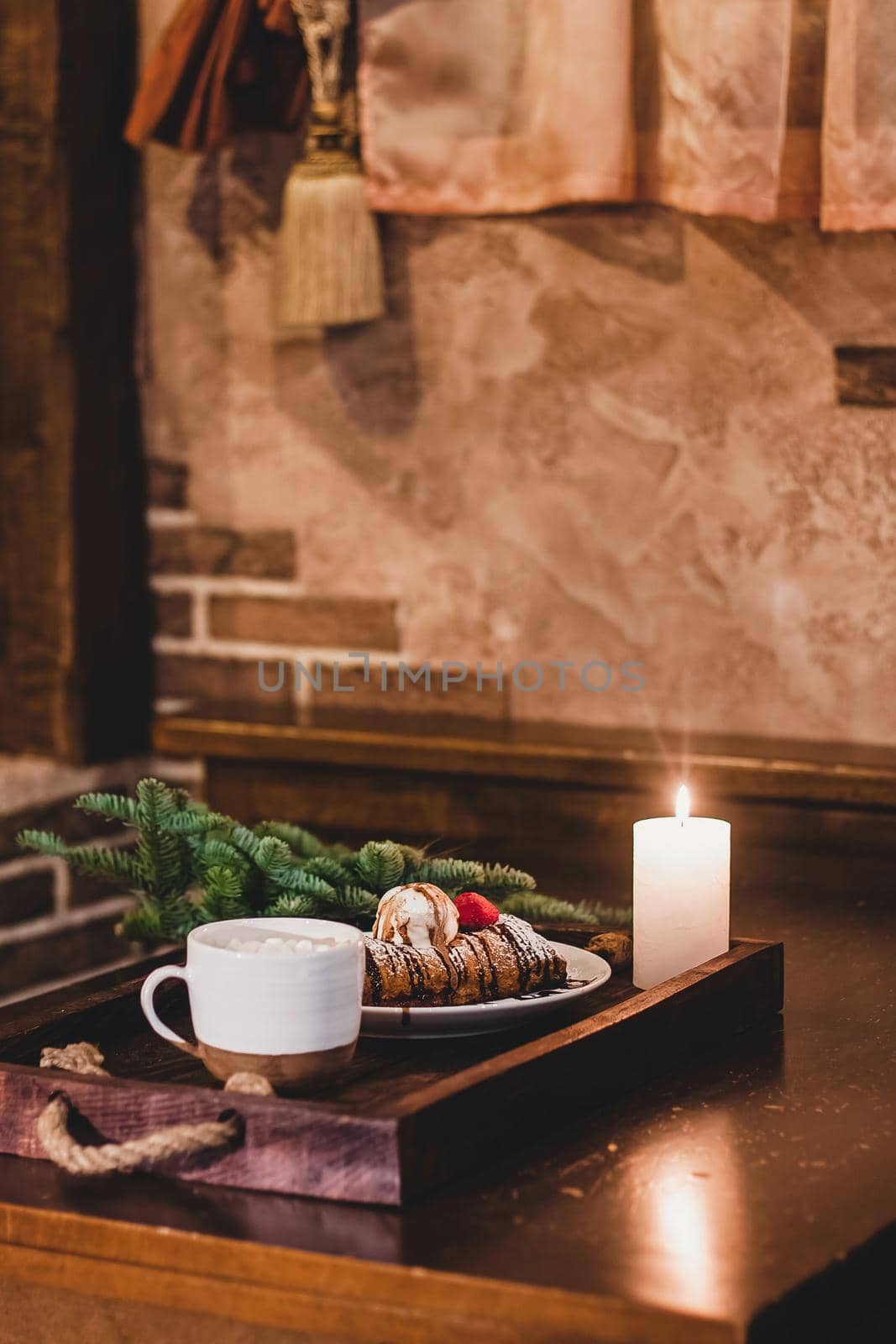 Closeup of a strudel with a strawberry on a Christmas plate near bamboo branch. Christmas breakfast on a wooden table