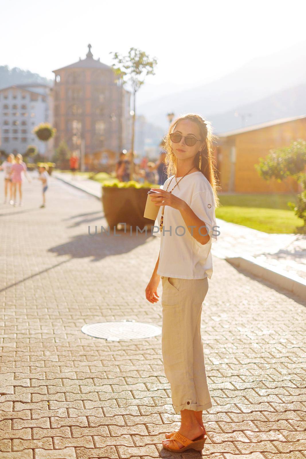 Beautiful young woman walking on the street with cup of coffee, full-length portrait.