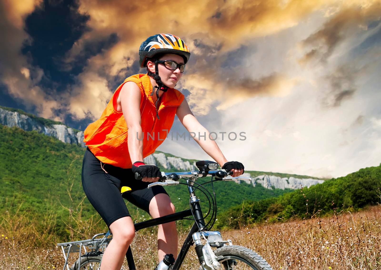 A young female riding a mountain bike outdoor at sunset