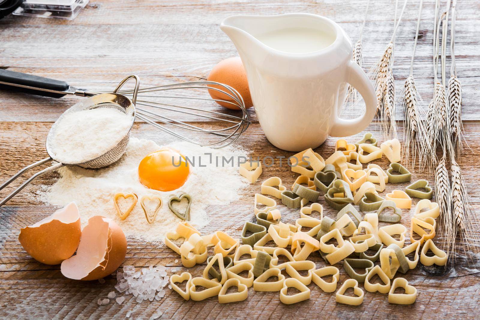 Heart shaped pasta and other products on a wooden textured table