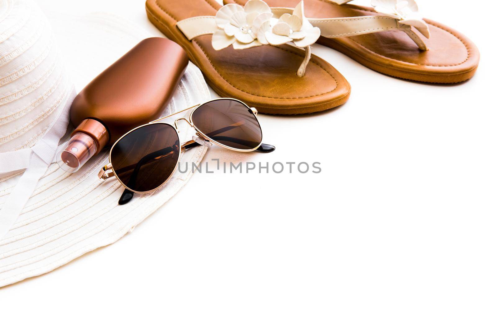 Beach accessories. Summer shoes and hat with sunglasses and suntan lotion on a white background