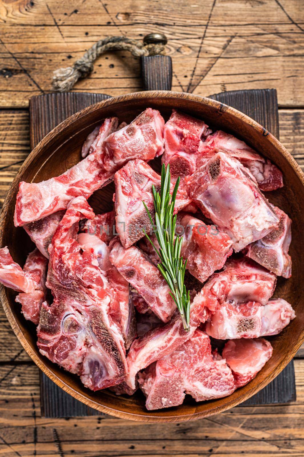 Fresh Raw meat on the bone diced for goulash in a wooden plate. Wooden background. Top View.