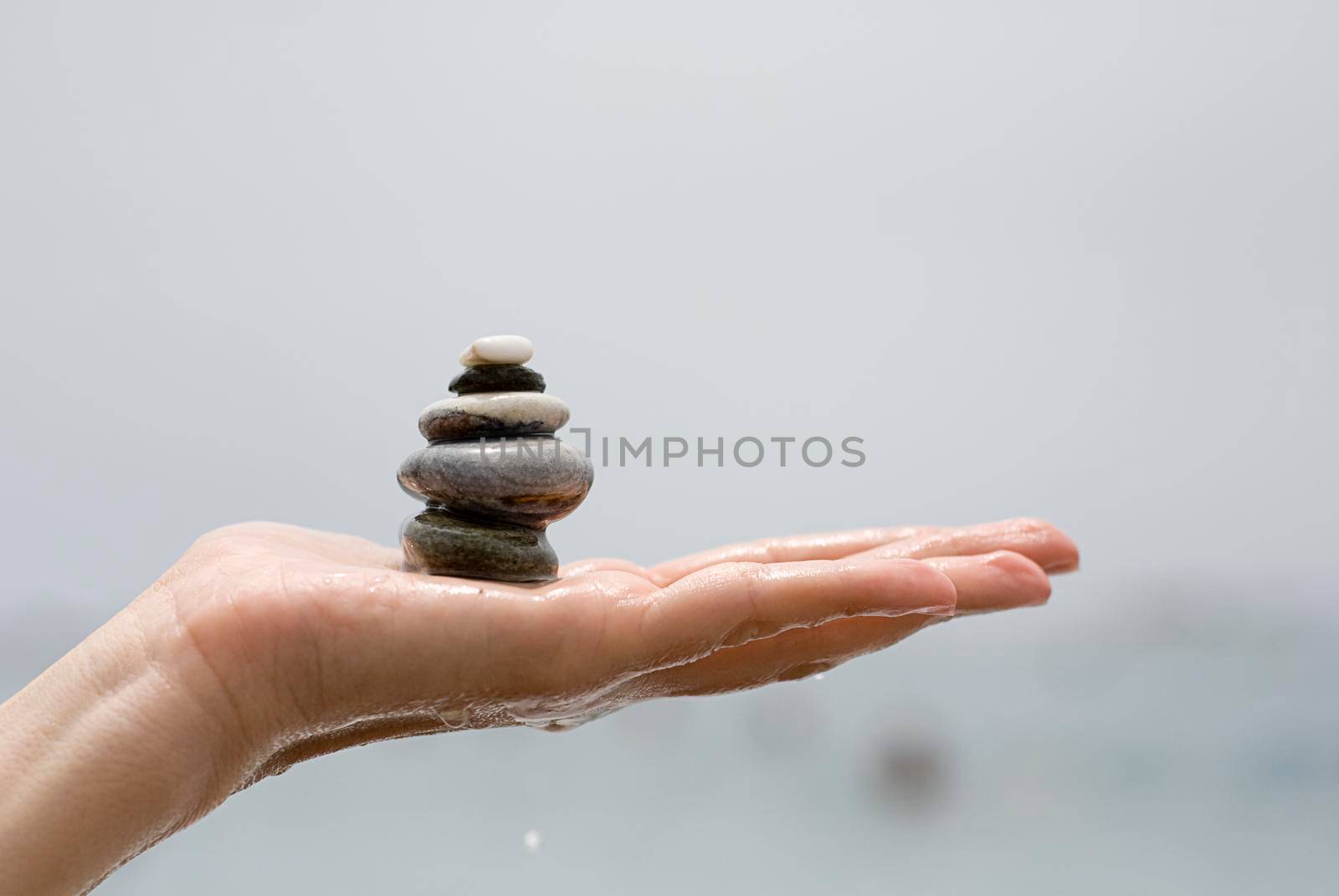 Gravel pile in woman's hands with sea background by javiindy