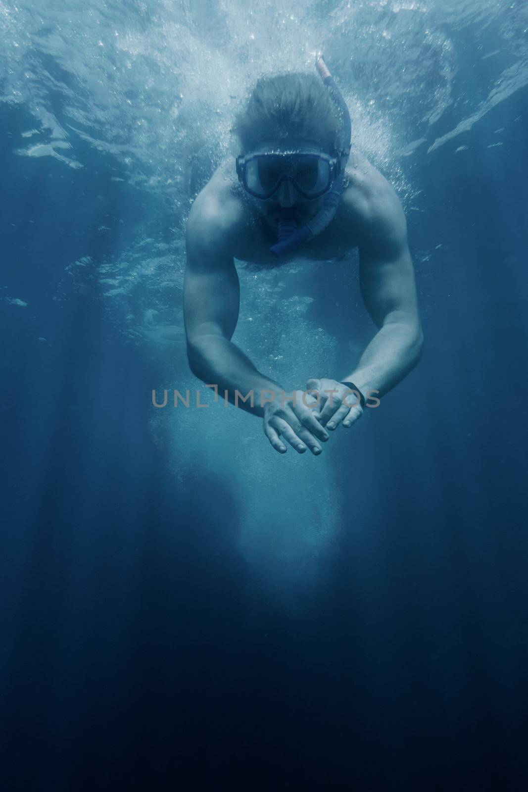 Young man in scuba mask diving underwater sea surface. Copy-space in down part of image.