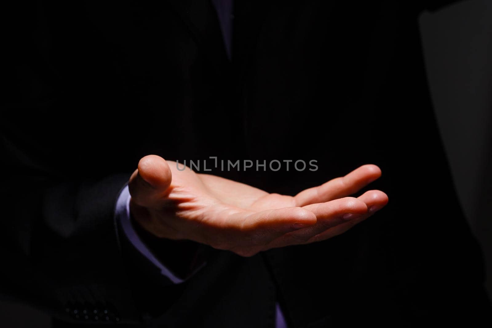 Businessman in blue suit presenting empty palm - it can be used to advertise product on his hands.