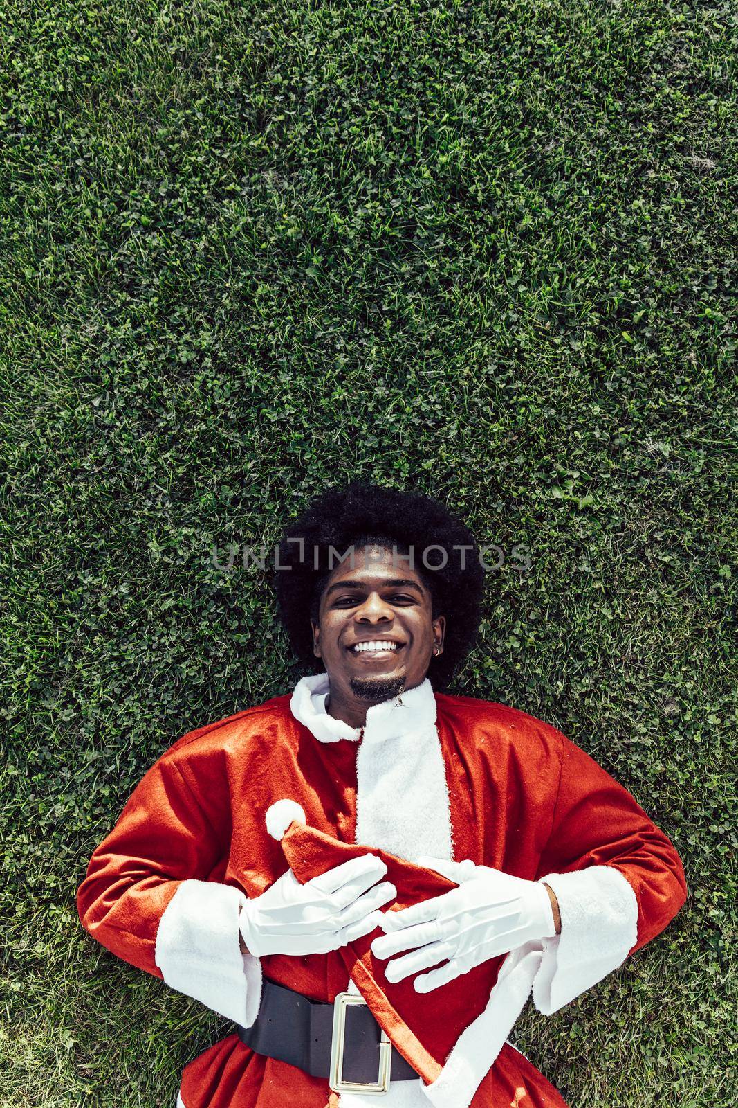 happy afro santa claus relaxing on the grass, vertical copy space by ALVANPH