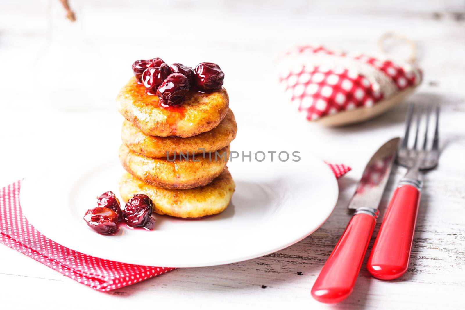 cheese pancakes with cherry jam on the plate