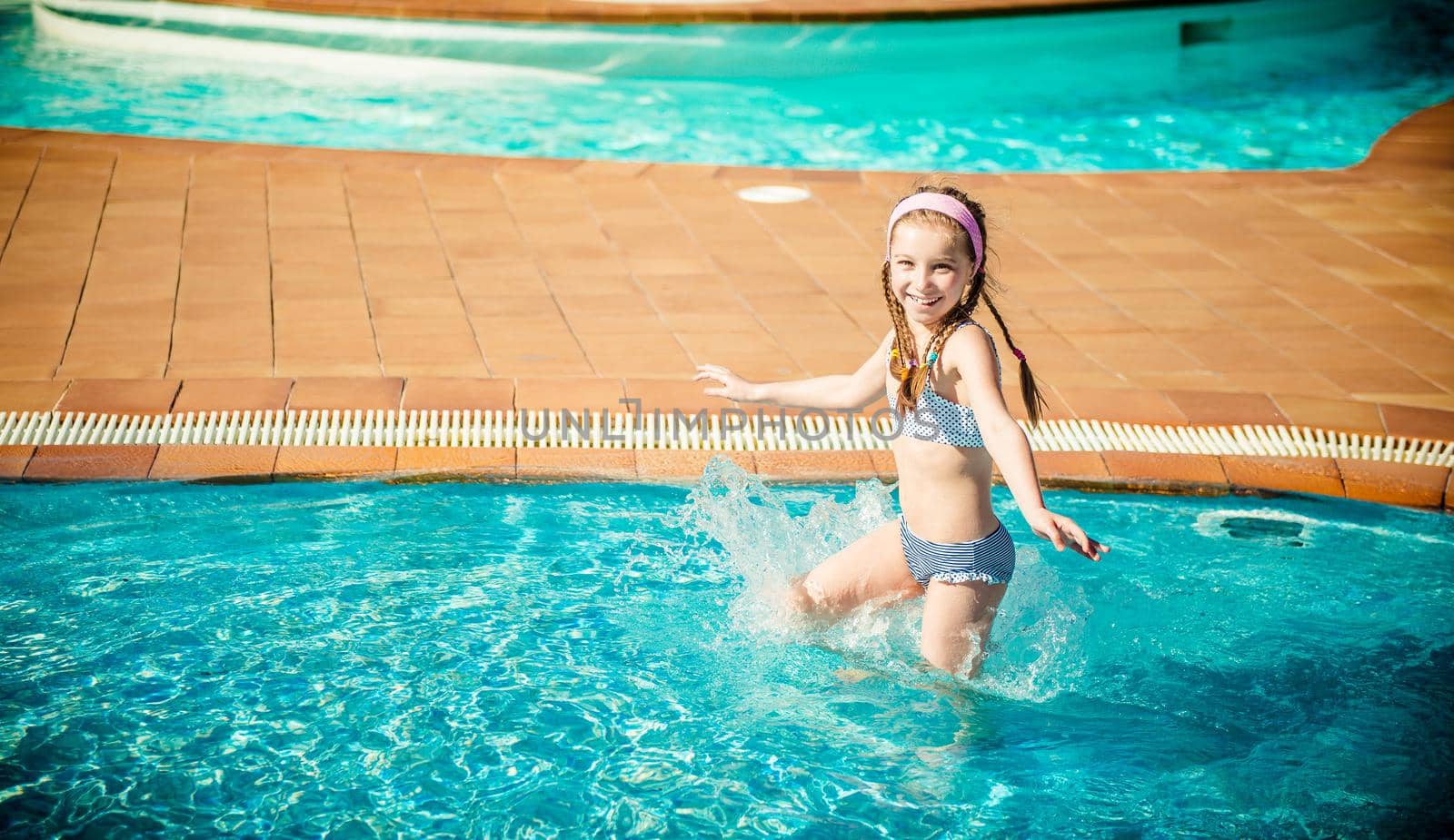 little happy girl swims in the pool