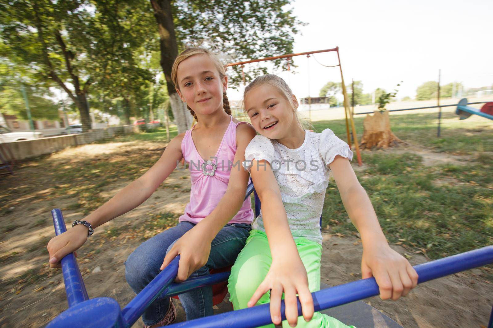 Two girls on the carousel at the playground