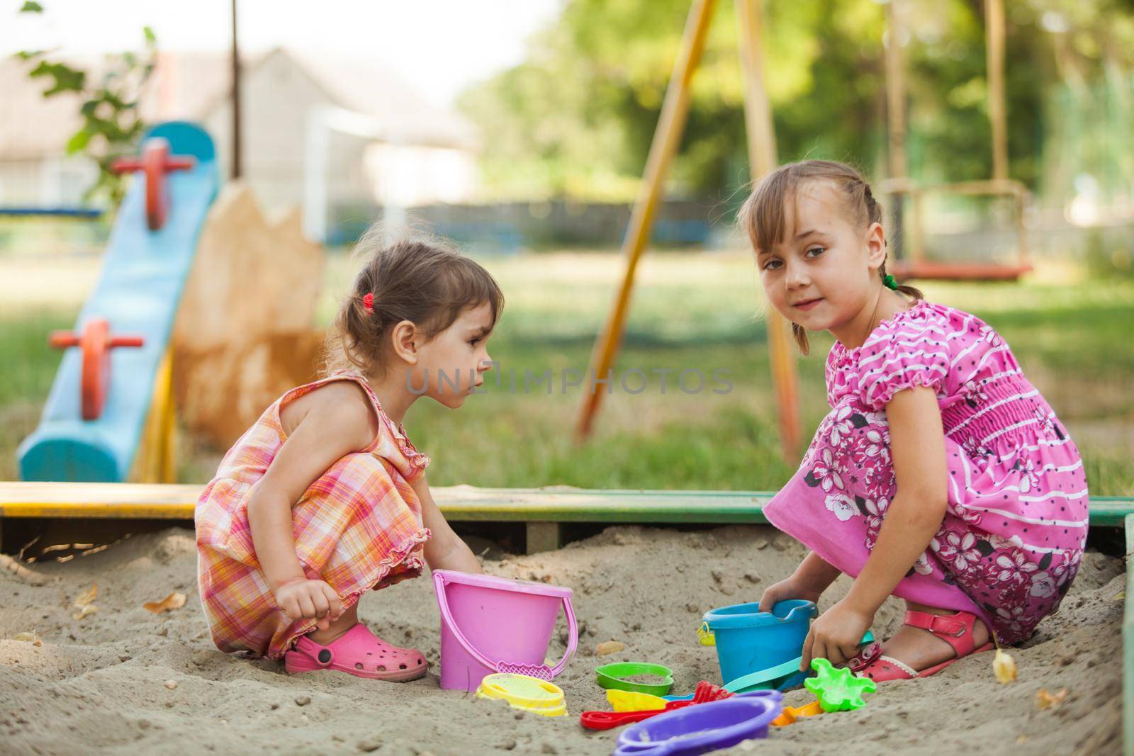 Two girls play in the sandbox at the playground
