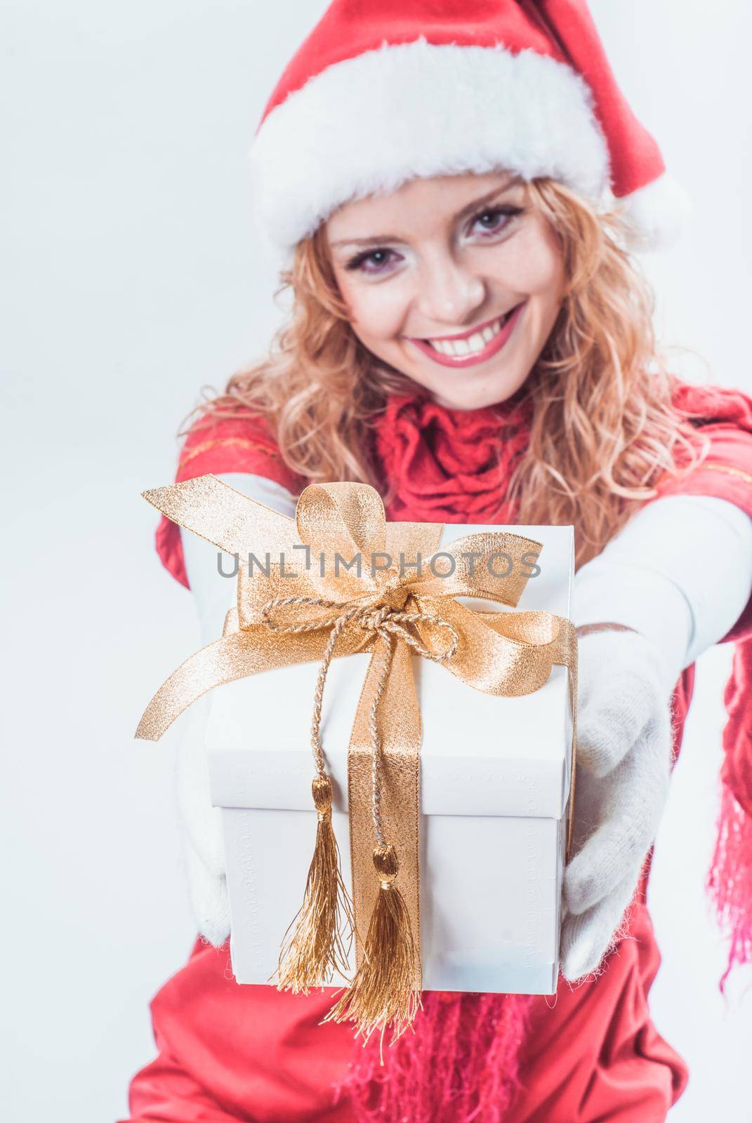 Christmas santa girl holds white giftbox with gold ribbon. Focus on the box