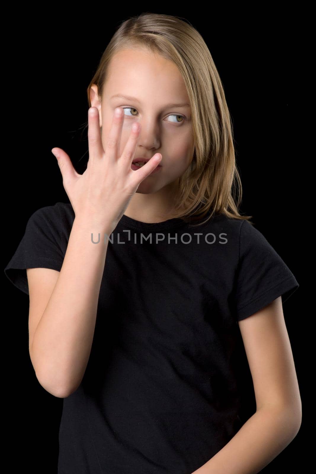 Close up portrait of teenage girl in black t-shirt gesturing against black background. by kolesnikov_studio