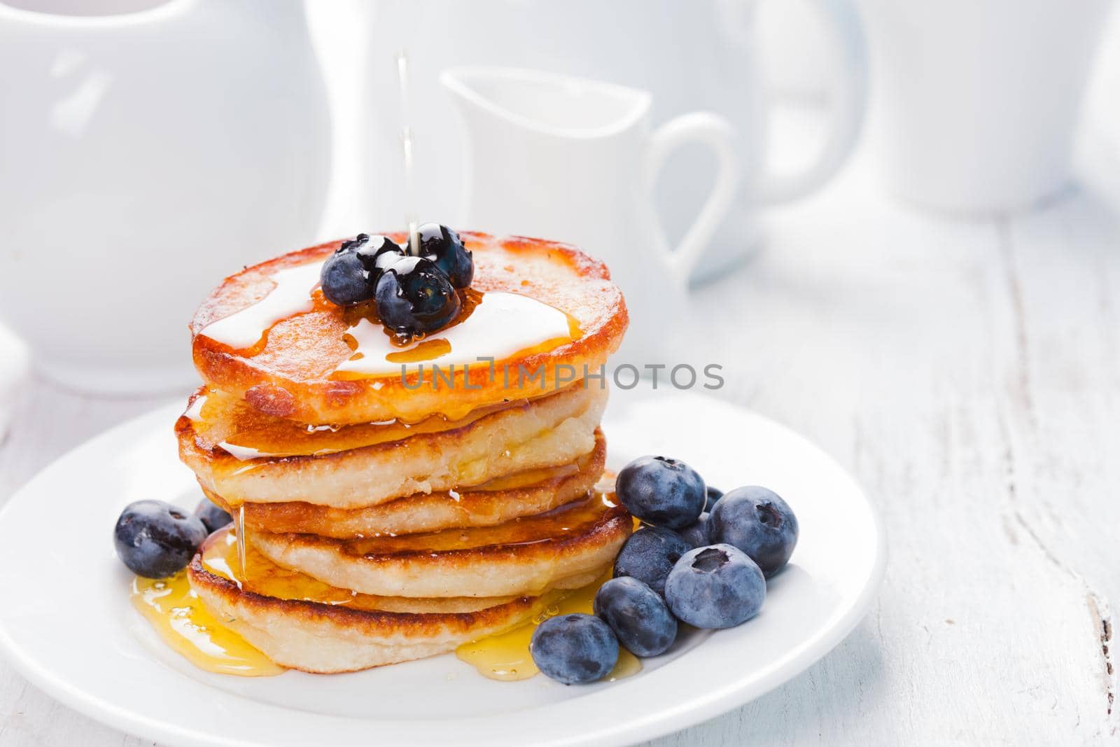 Pancakes with blueberry and honey on a white plate