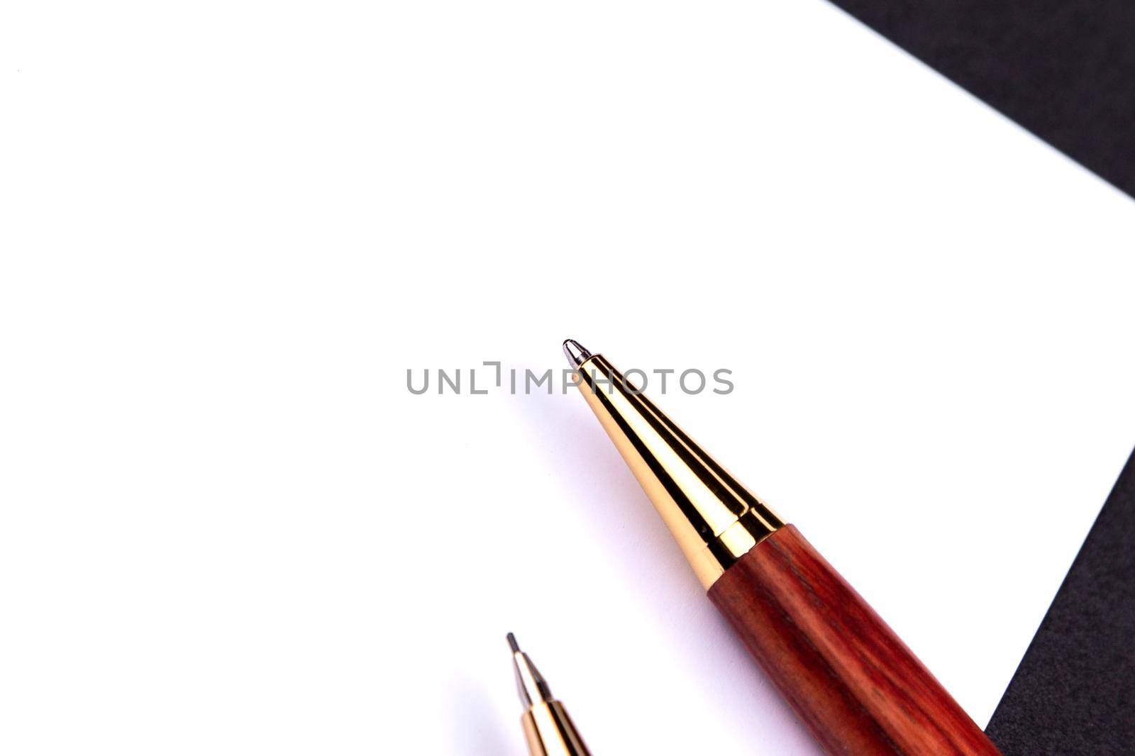 Luxury pen and mechanical pencil in wood and gold with a white sheet of paper.