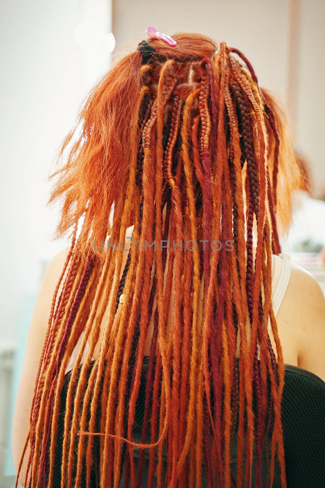 View from back of girl with colorful dreadlocks from kanekalon. Fashion beauty and stylish hair.