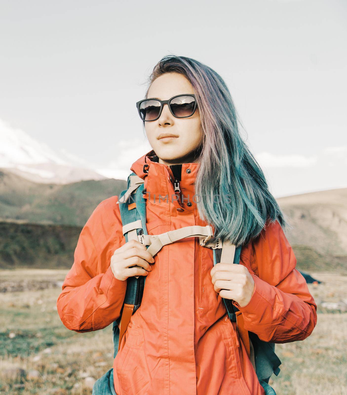 Beautiful hiker explorer young woman with backpack standing in the mountains outdoor.