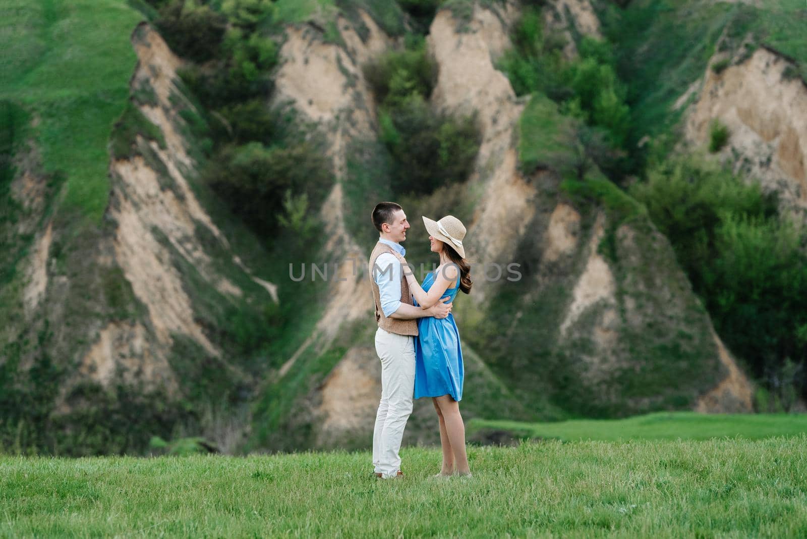 young couple a guy and a girl are walking in the green mountain hills