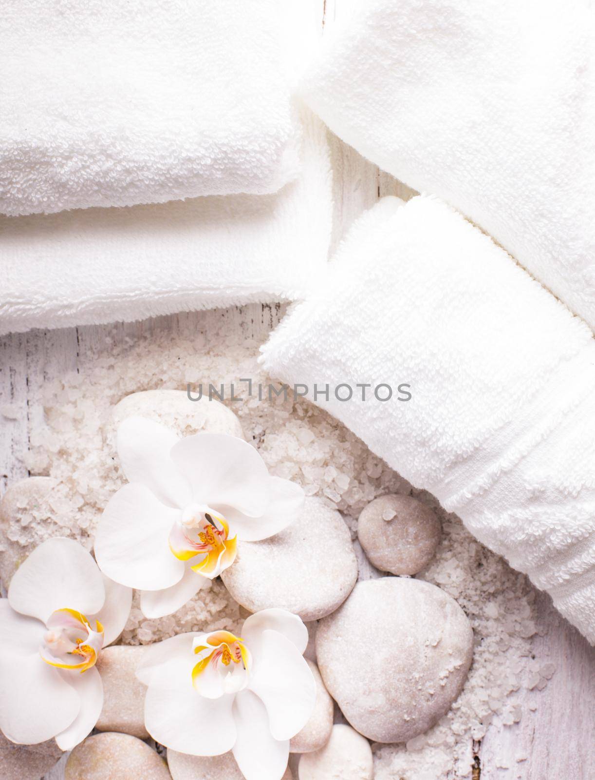 Sea salt, rebbles with orchids and white towels, spa concept