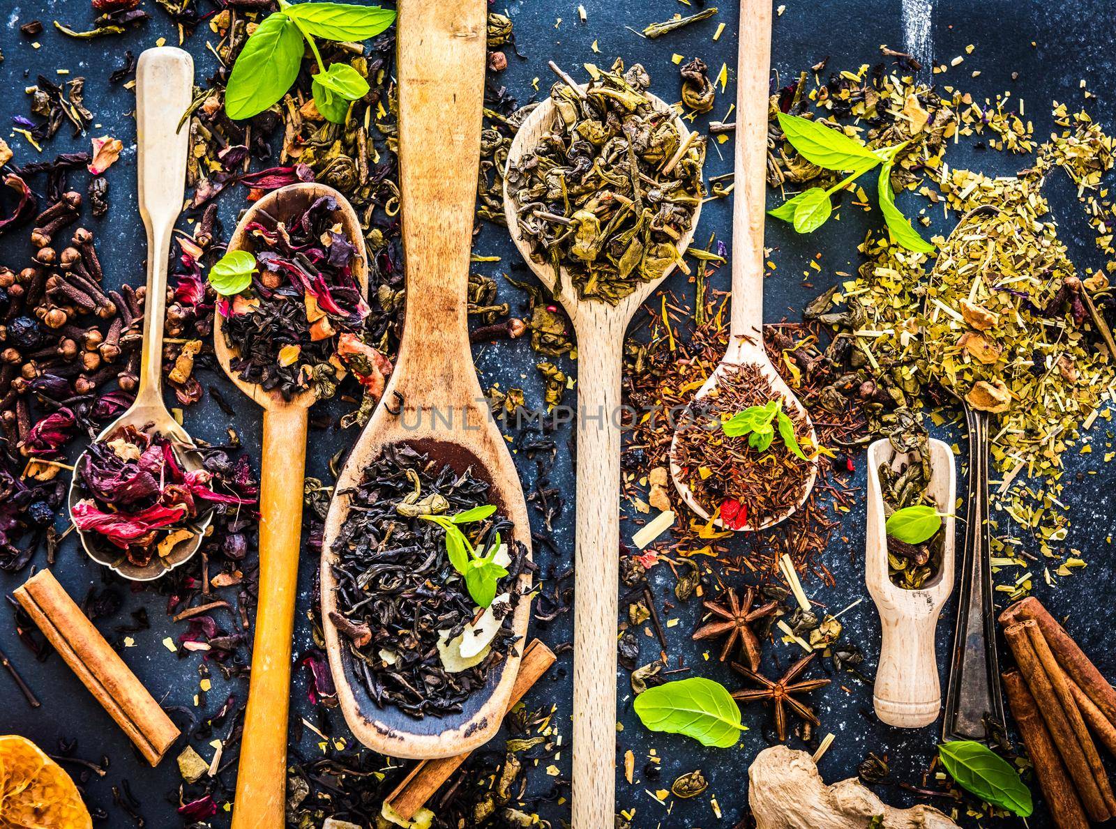Virious kinds of tea in wooden spoons on black table