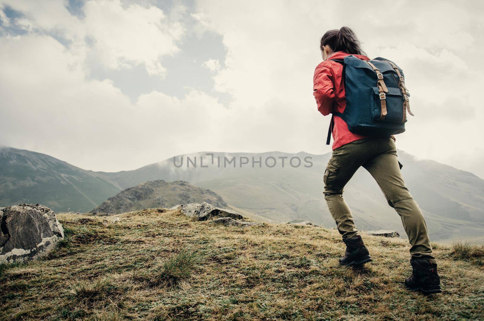 Explorer young woman with backpack going up on mountain outdoor.