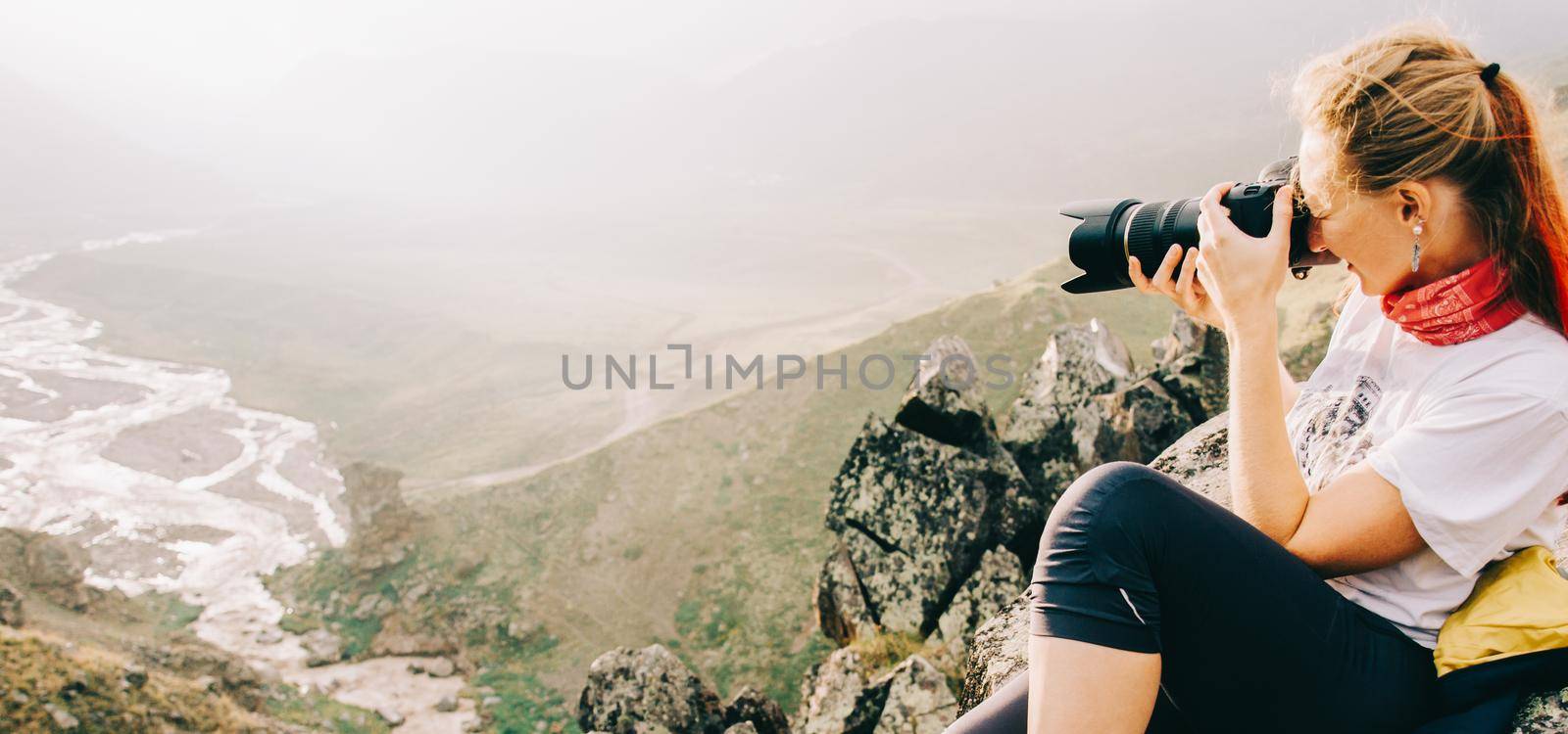 Beautiful traveler young woman photographing in the mountains.
