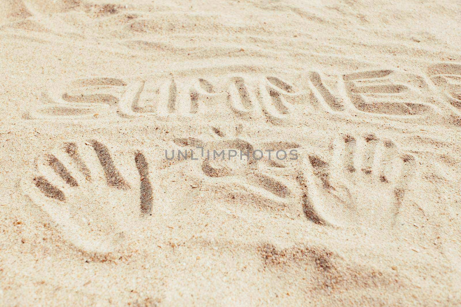 Inscription word summer and hand prints with drawing sun on sand, concept of vacations.