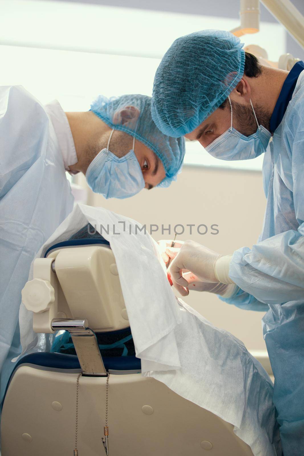 Two surgeons in blue robes make operation in surgery room by Studia72