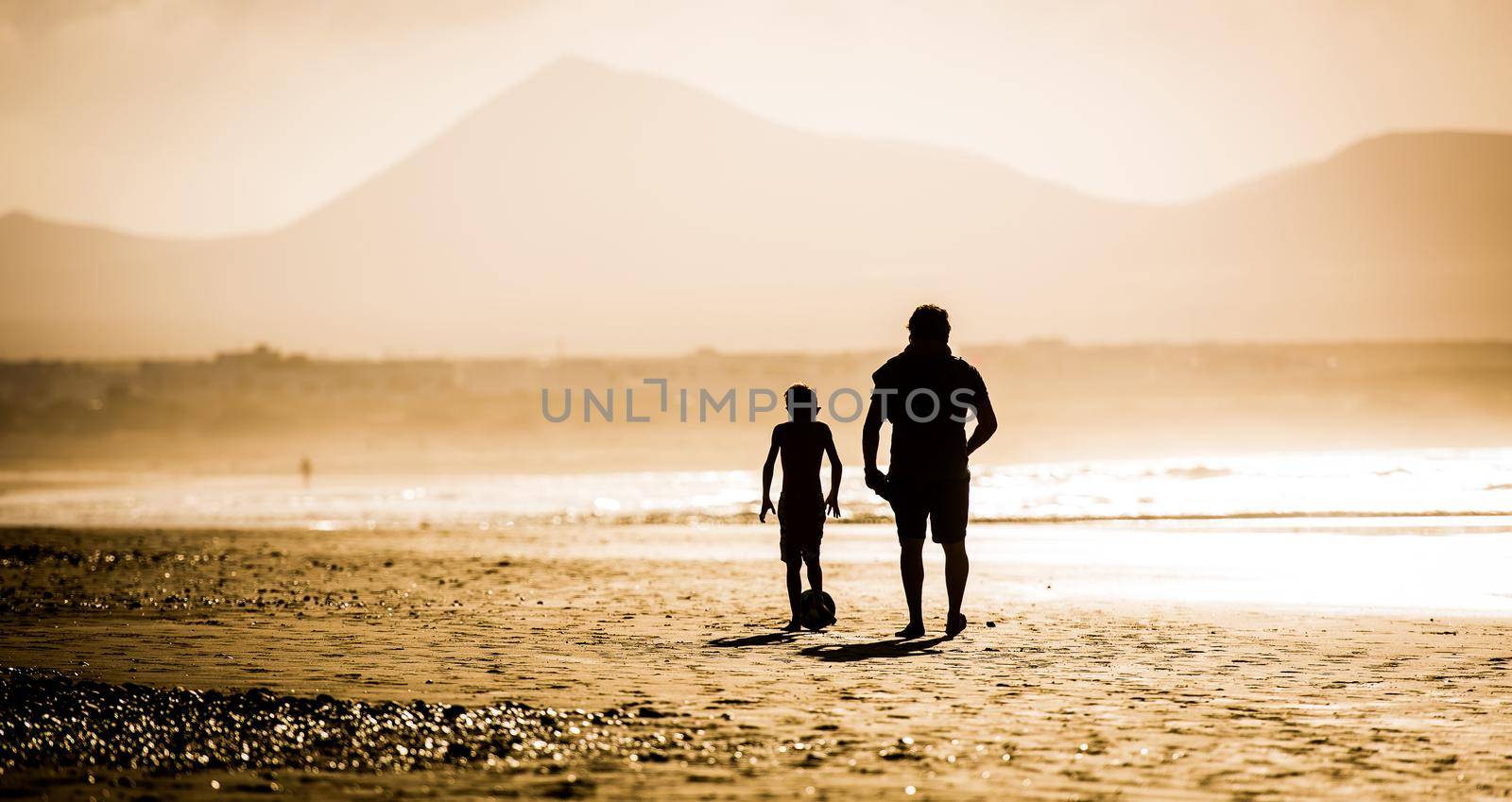 Silhouette of father and son on the beach