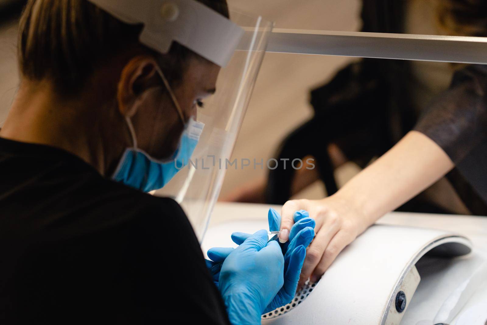 Aesthetician doing the manicure, filing the nails with a file to his client in a beauty center. Business and beauty concepts