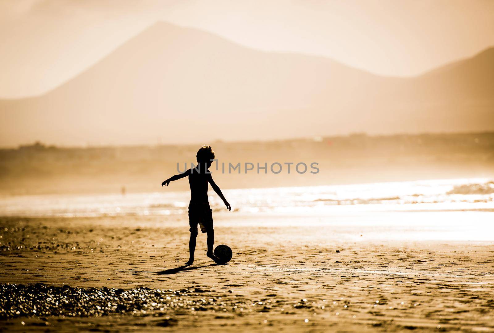 Silhouette of boy on the beach, playing football