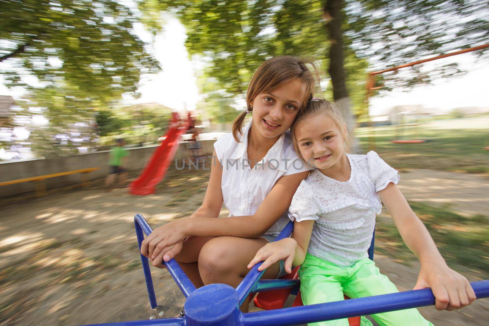 Two girls on the carousel at the playground