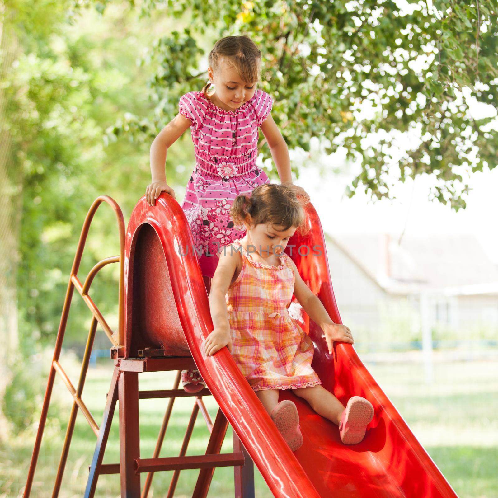 Two preschool girls on the slide at the playground