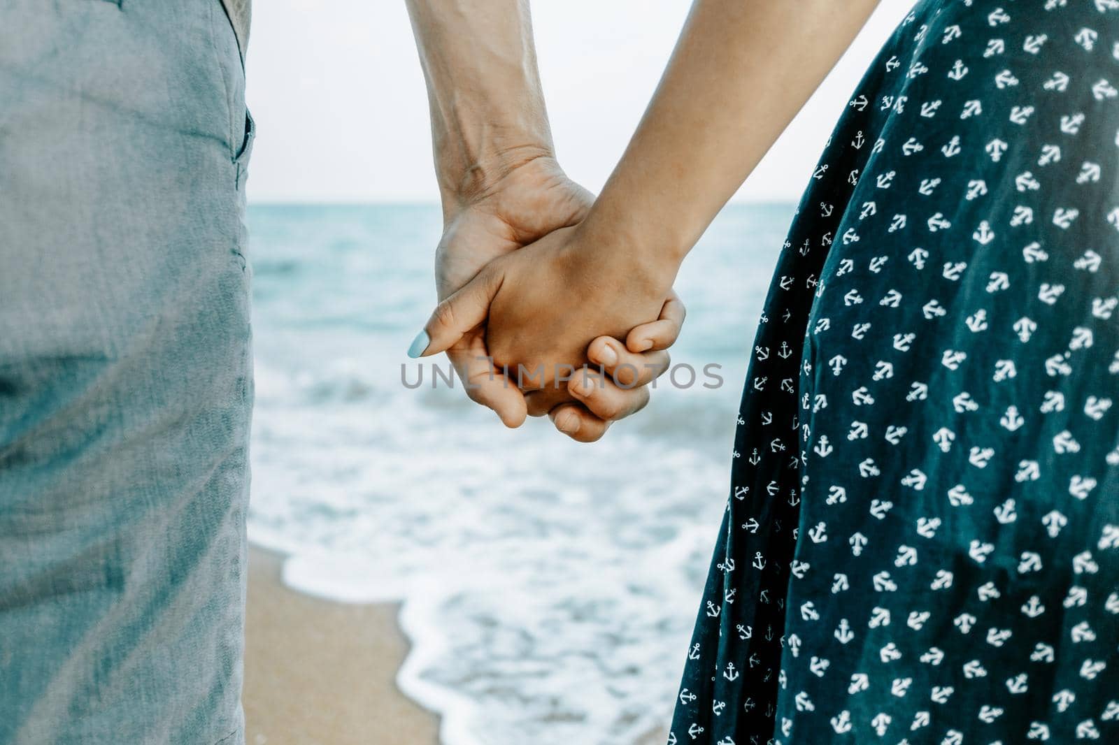 Couple in love holding hands on sea coast, close-up. by alexAleksei