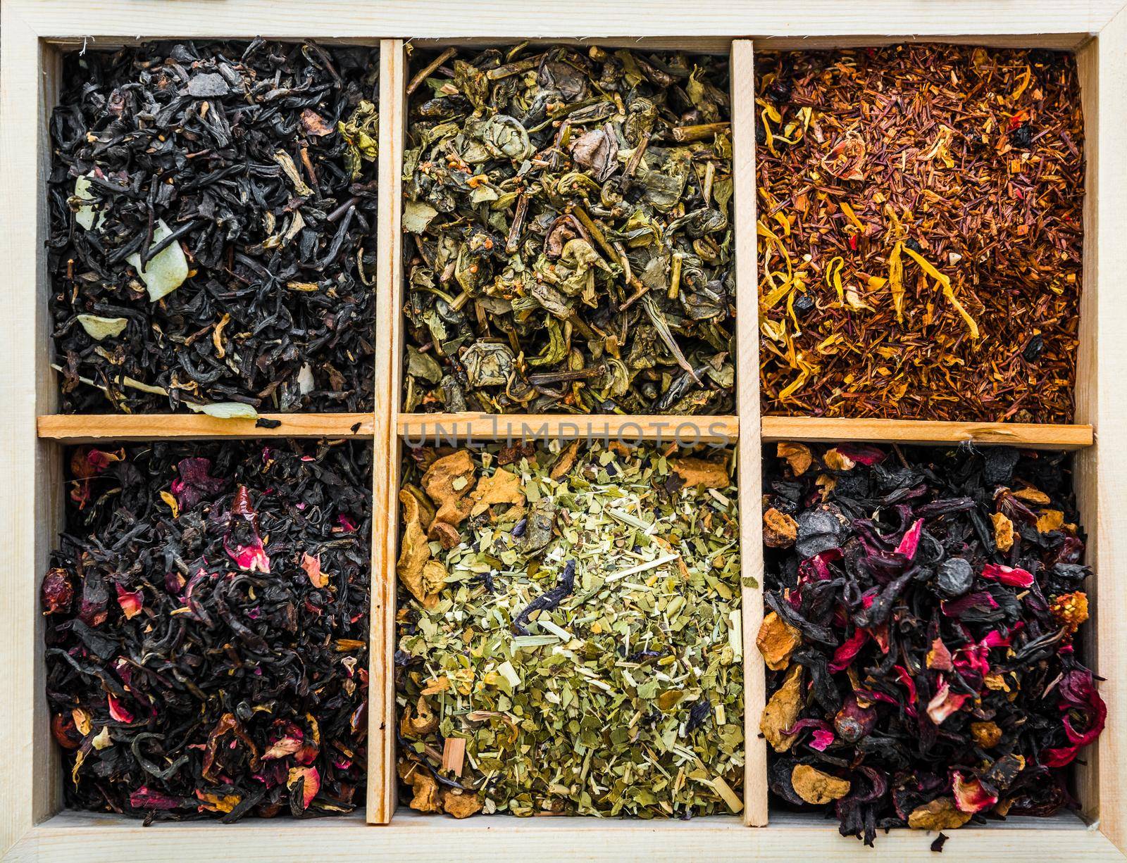 aromatic dry teas in wooden box and spoons on wooden background