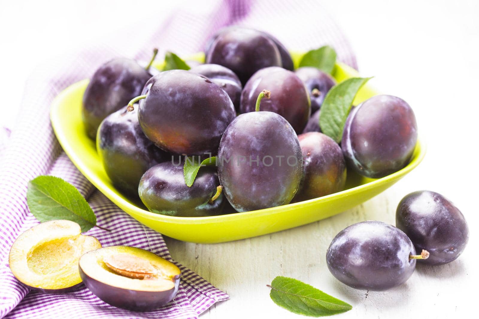 Fleshy plums in a bowl on the table