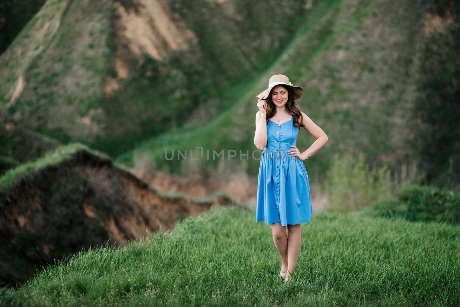 young girl in a straw hat with large brim on mountain green slopes