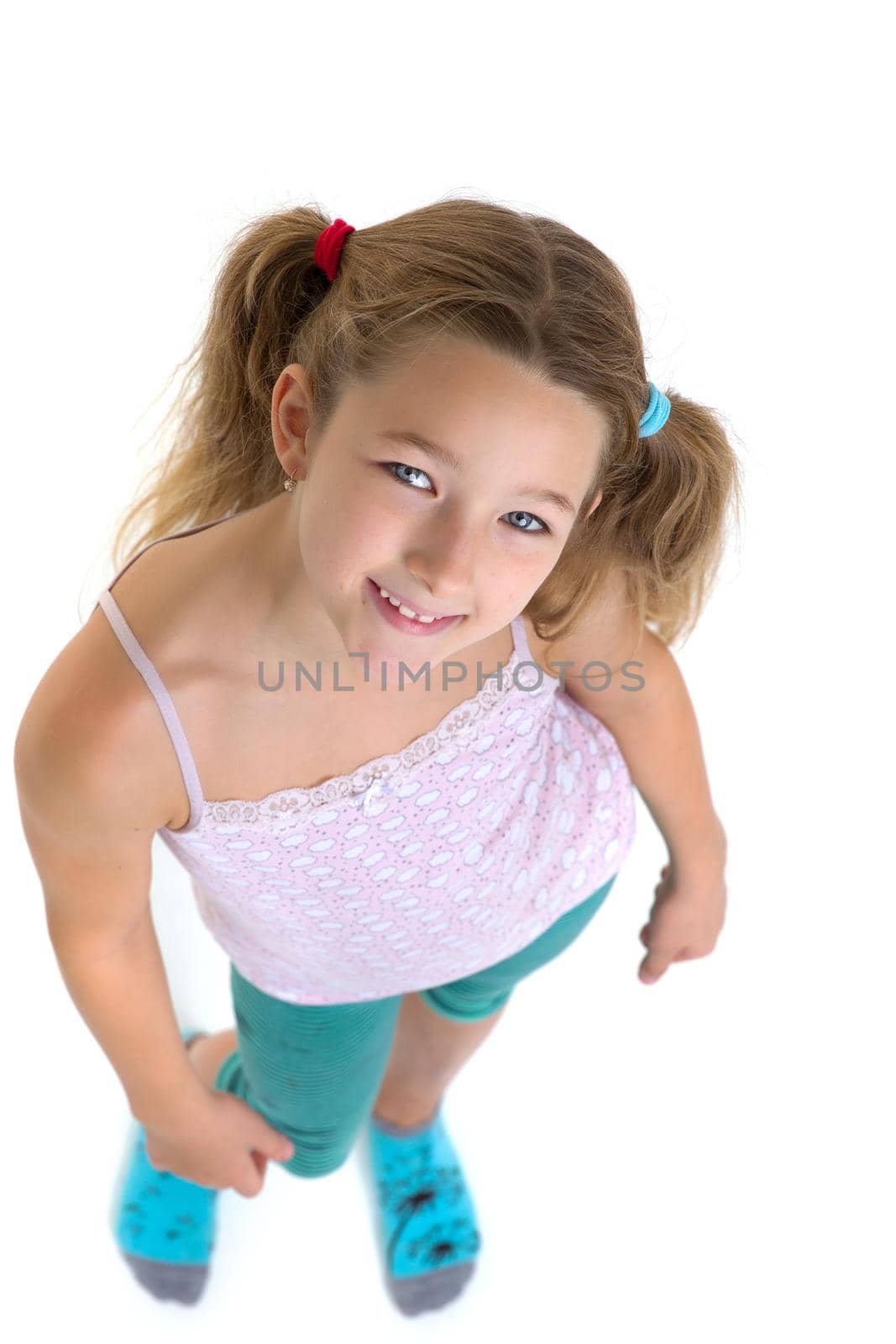 Preteen girl looking up at camera. Above view portrait of child posing in studio against white background. Cute girl wearing casual clothes