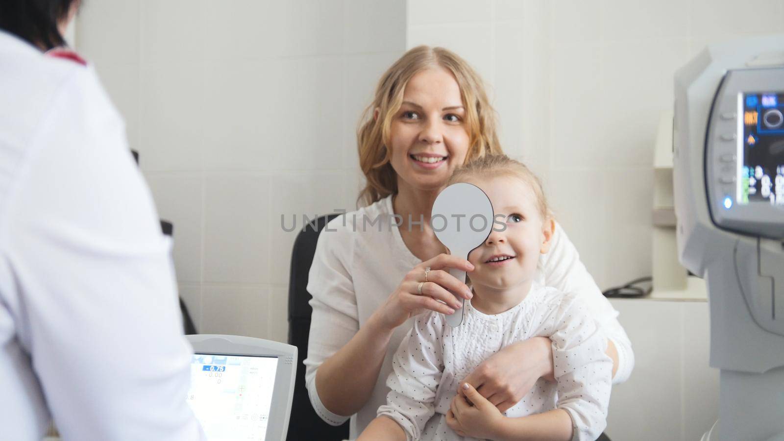 Optometrist in clinic checking little child's vision - medicine, wide angle