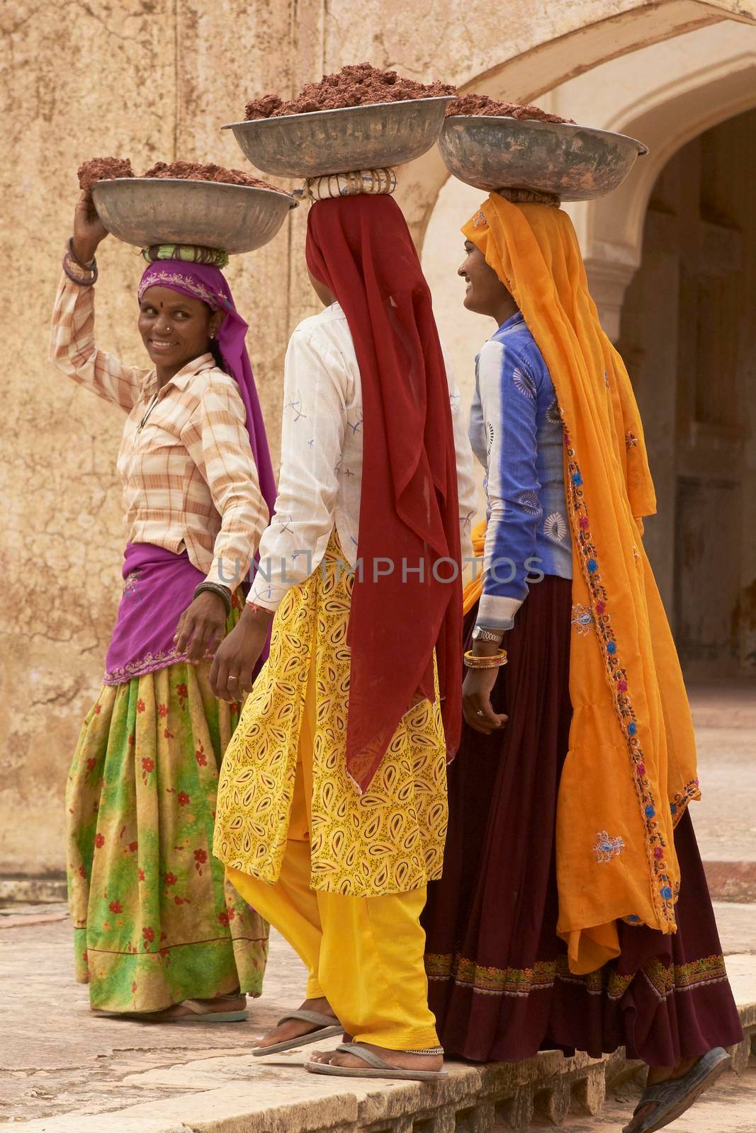 JAIPUR, RAJASTHAN, INDIA - JULY 30, 2008: Female laborers transporting water and plaster in bowls carried on the head during the restoration of a palace inside Amber Fort in Jaipur, Rajasthan, India.
