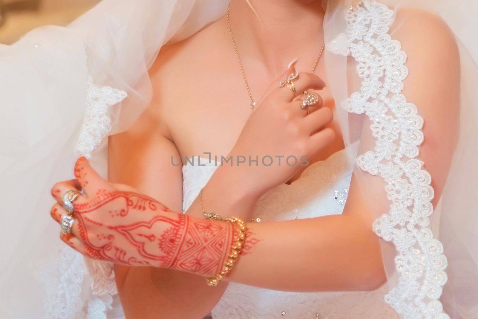 The bride holds the fat. The bride has handset, rings and bracelets. Elegant Wedding Ring with Beautiful Henna of Bride Hand
