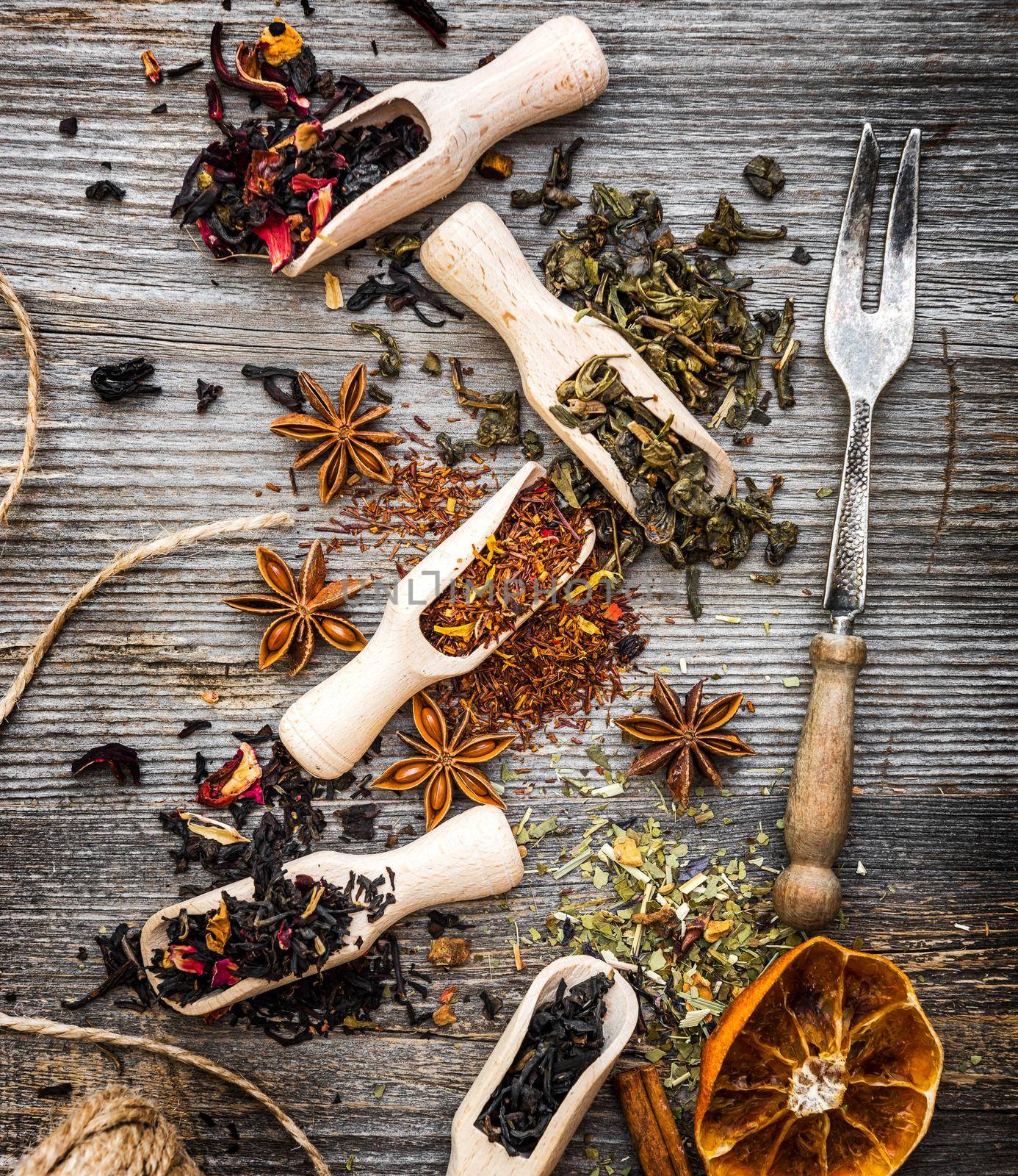 odorous dry teas in scoops on wooden background