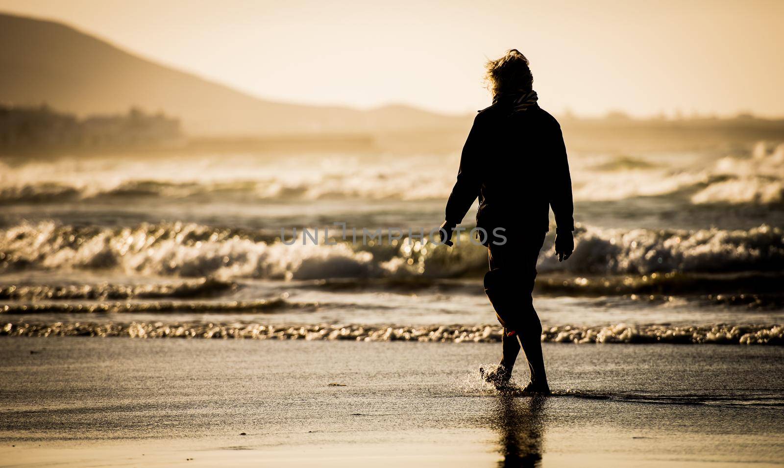 Silhouette of the man, walking on the ocean beach