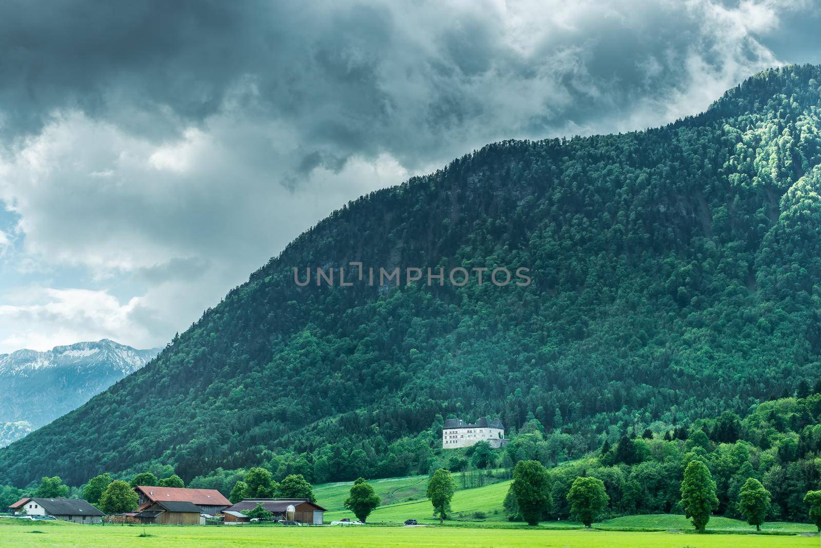 village near forest in mountains with peaks in clouds