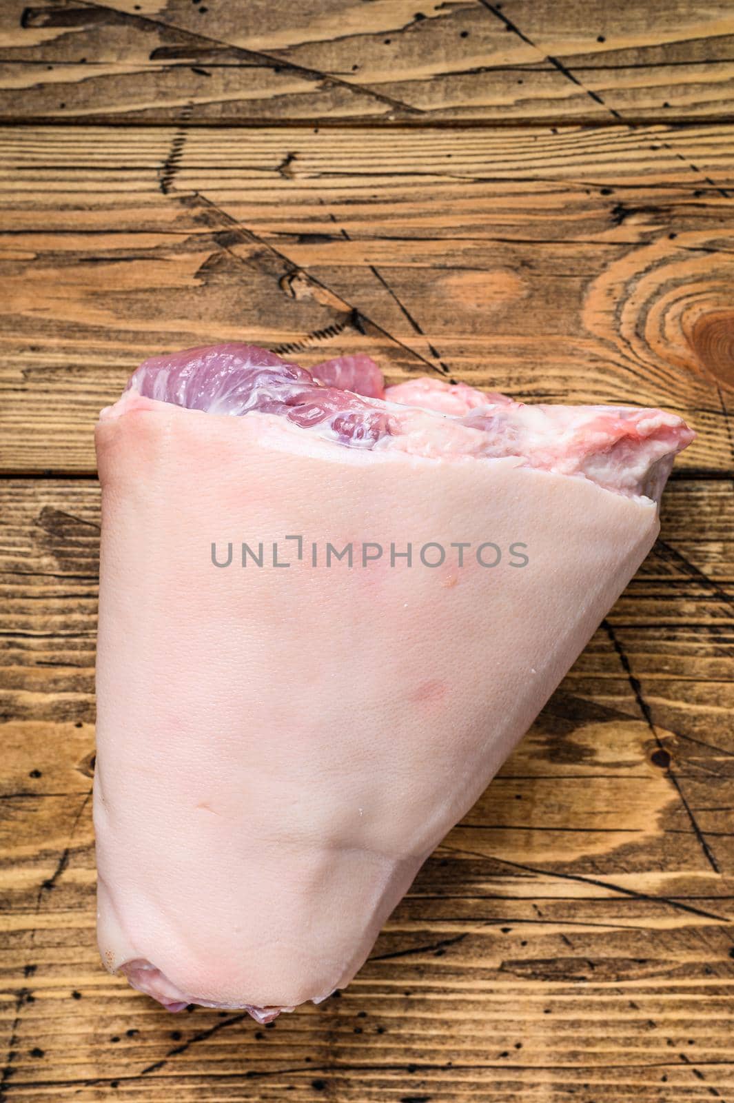 Raw pork knuckle meat on a kitchen table. Wooden background. Top view.