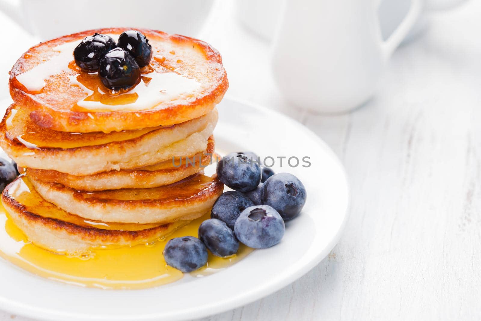 Pancakes with blueberry and honey on a white plate