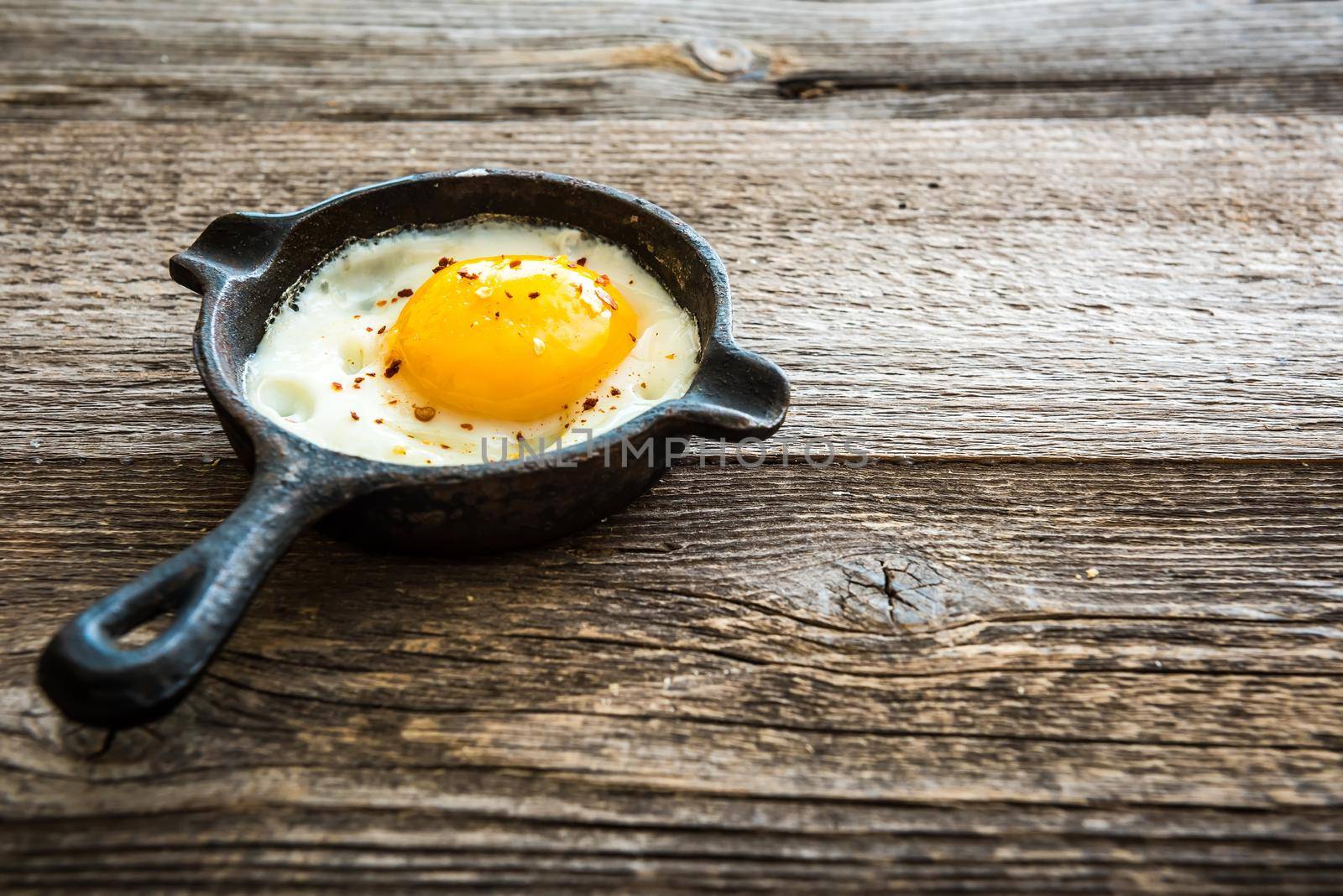 fried egg in a pan on wooden background, breakfast