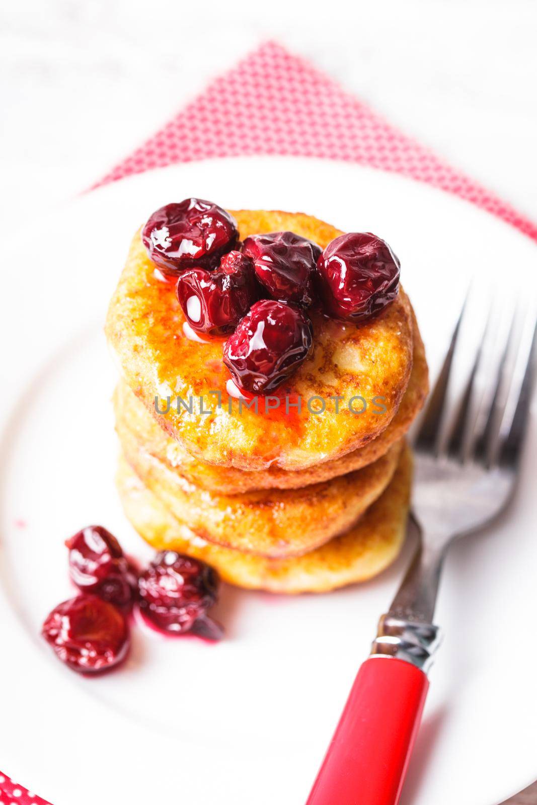 cheese pancakes with cherry jam on the plate